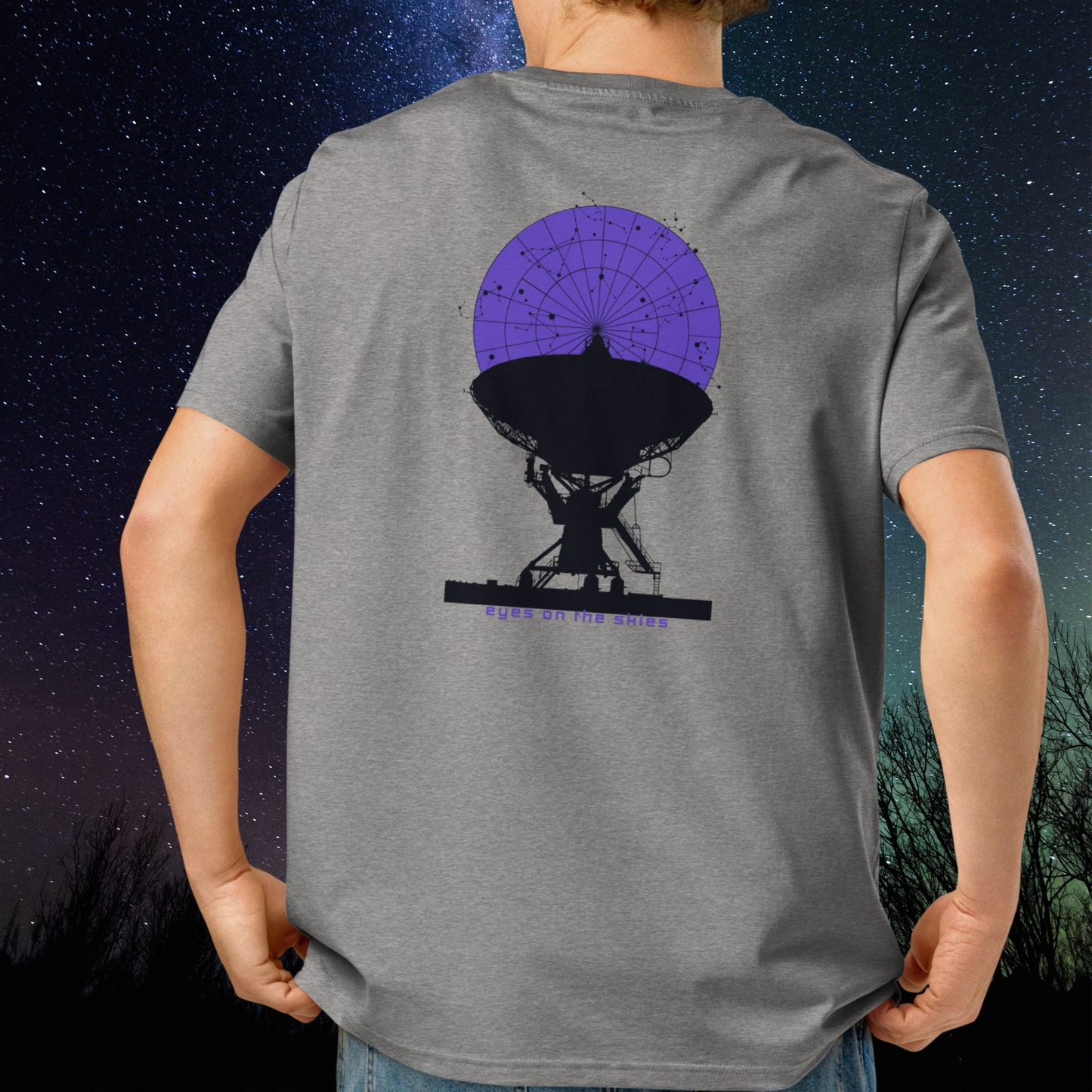 Person wearing a gray Stellarwear t-shirt with a radio telescope graphic on the back, against a starry night sky.
