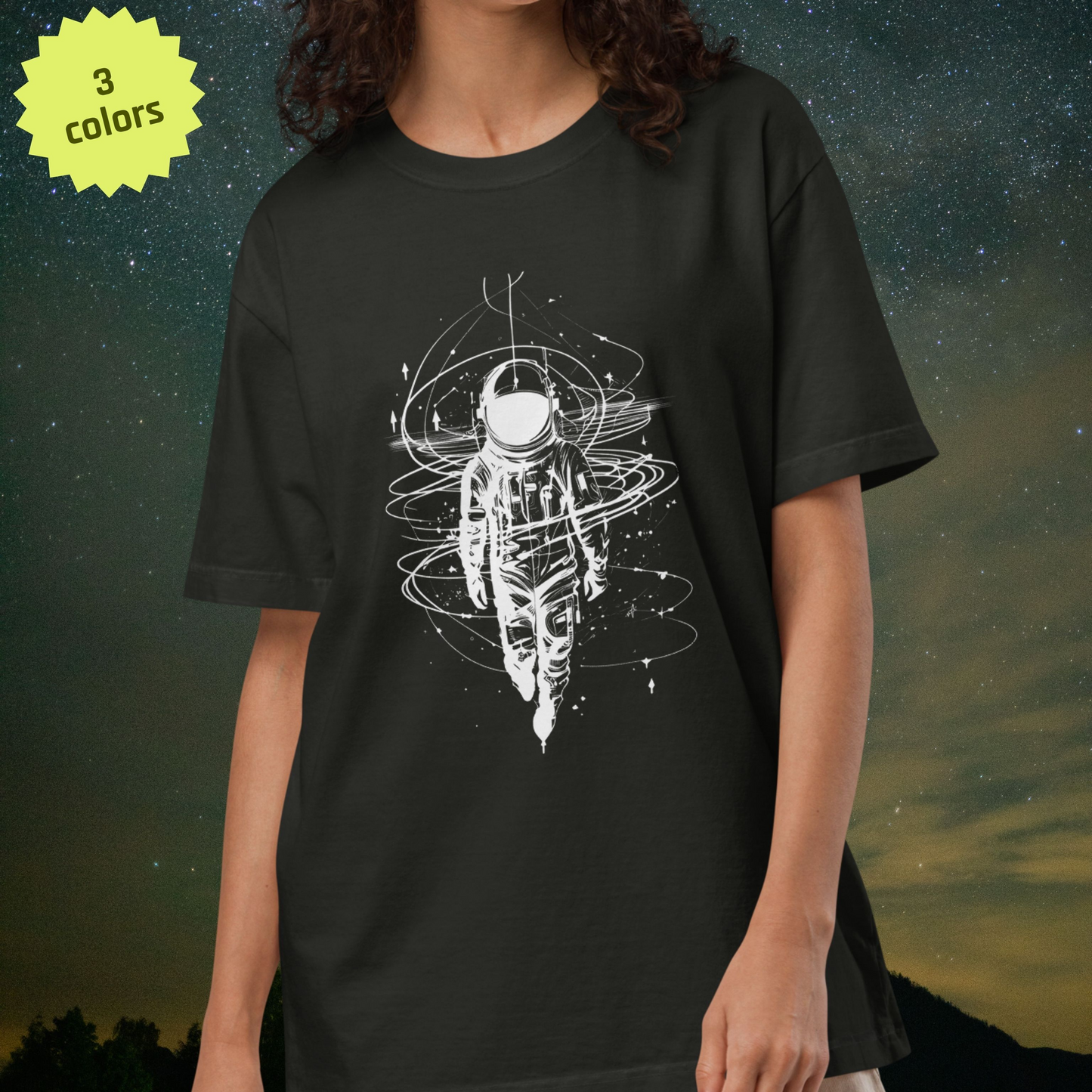 Person wearing a black Stellarwear t-shirt with a white astronaut graphic design against a starry night sky background