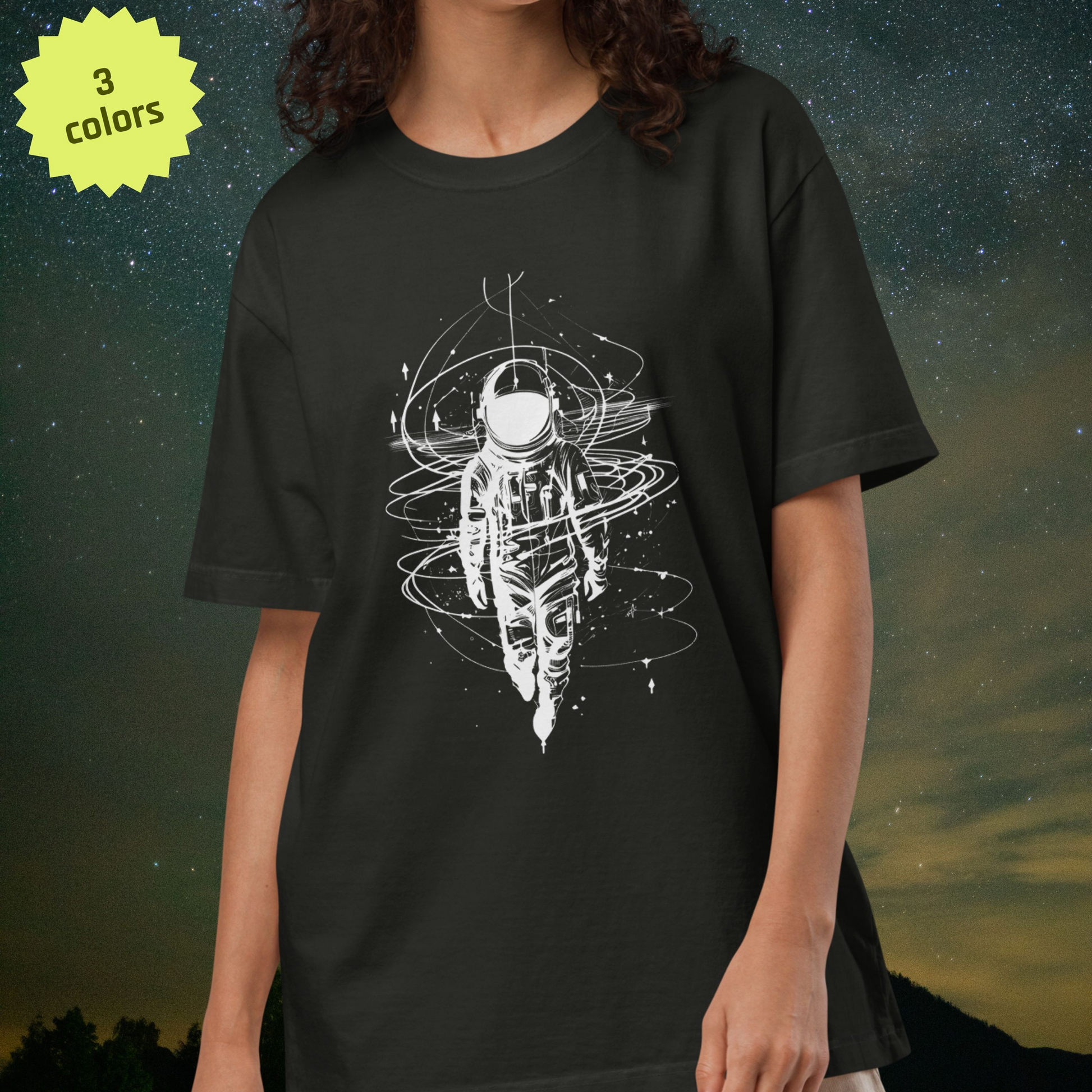 Person wearing a black Stellarwear t-shirt with a white astronaut graphic design against a starry night sky background