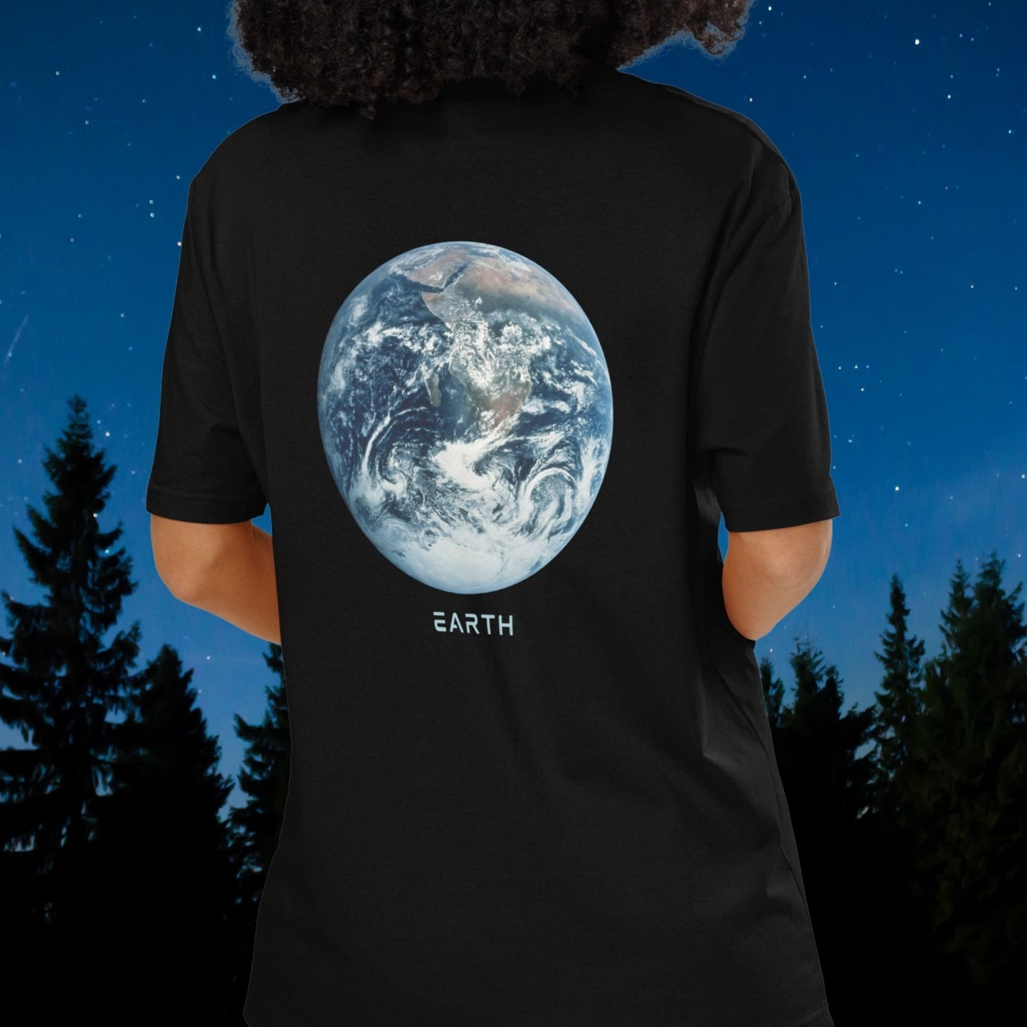 Person wearing a Stellarwear black t-shirt with an Earth graphic and 'EARTH' text, standing against a night sky with trees.