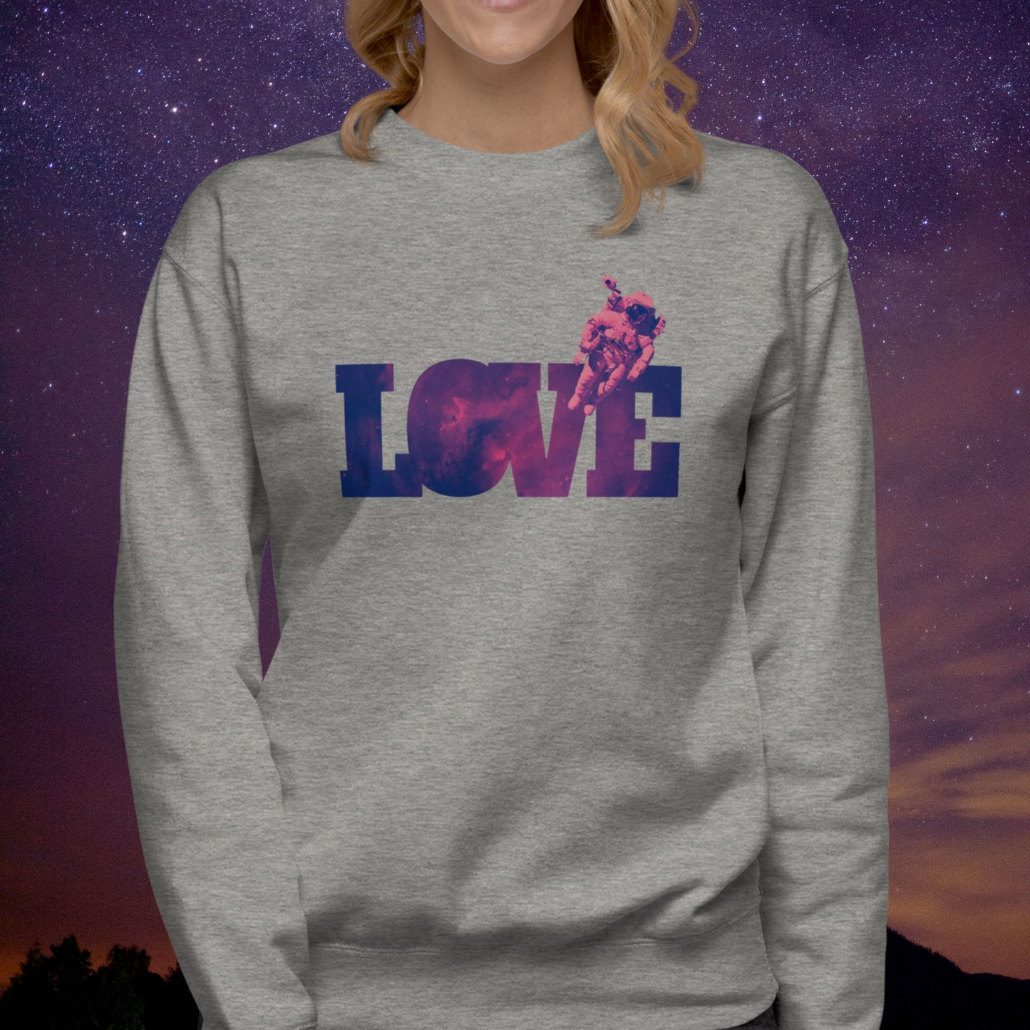 Person wearing a gray Stellarwear sweatshirt with 'LOVE' astronaut graphic design against a starry sky background