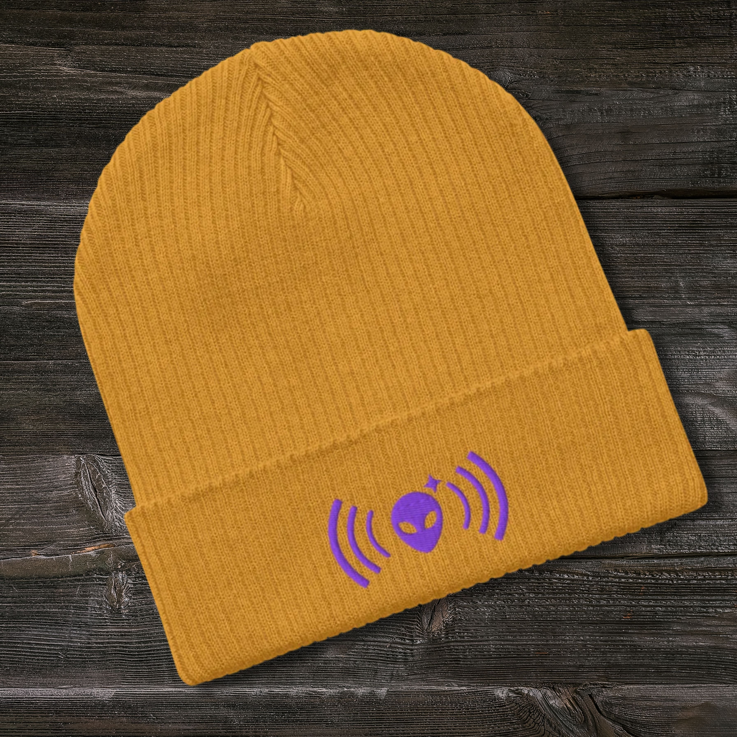 Yellow Stellarwear beanie with purple graphic on a wooden surface