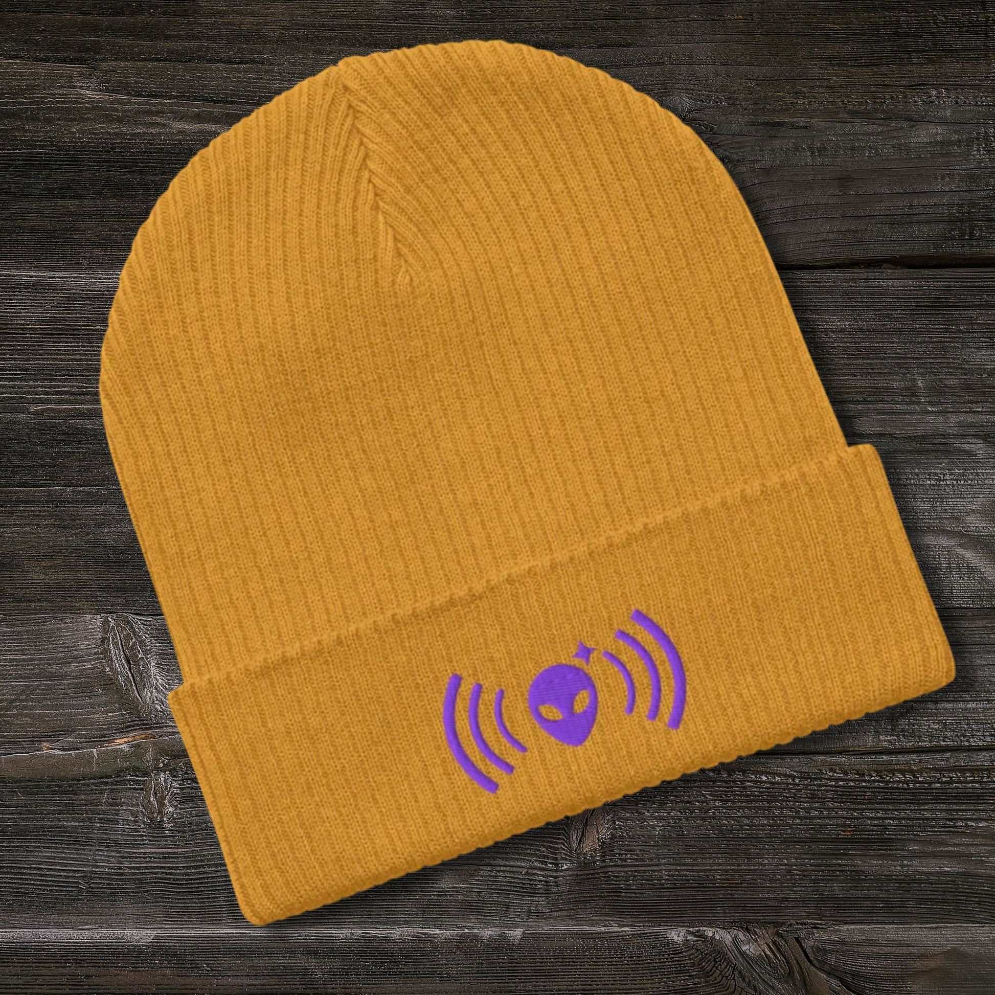 Yellow Stellarwear beanie with purple graphic on a wooden surface