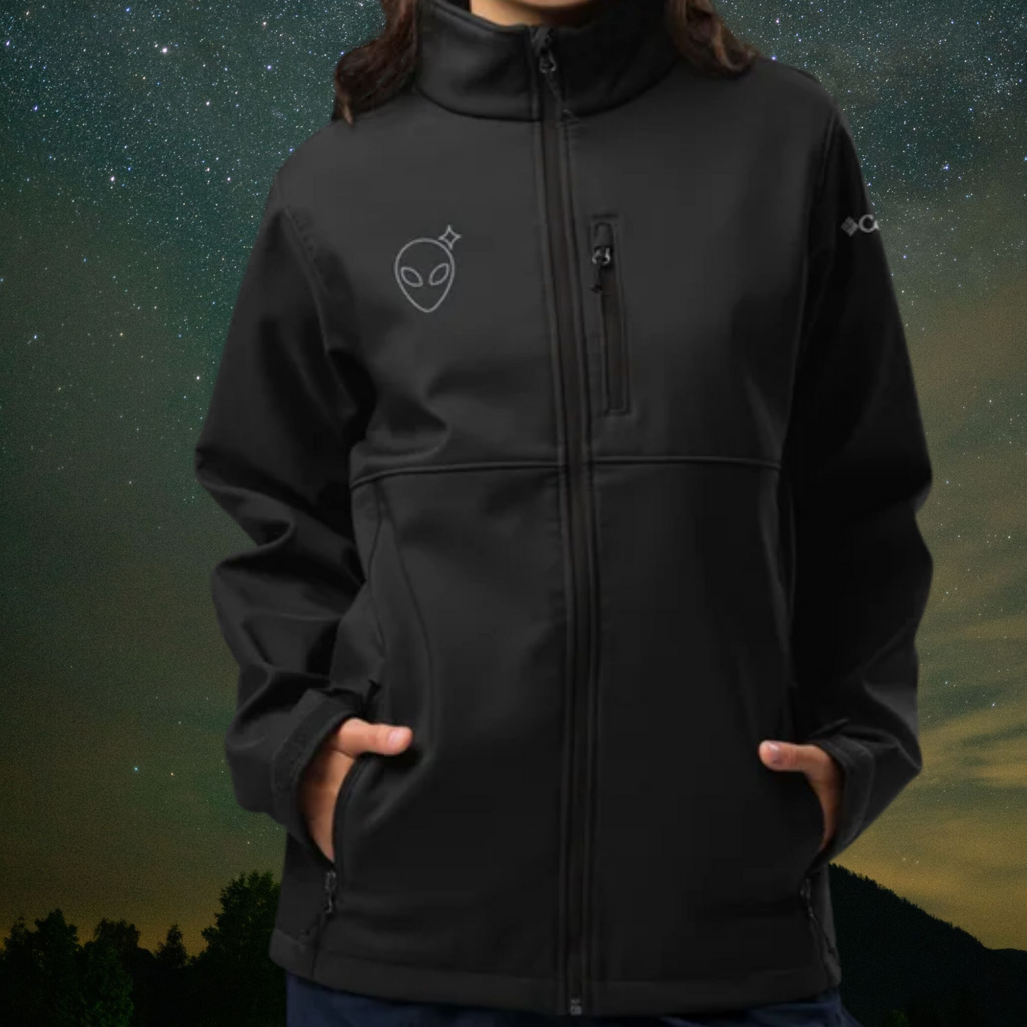 Person wearing a Stellarwear black jacket with an embroidered Alienhead against a night sky background.