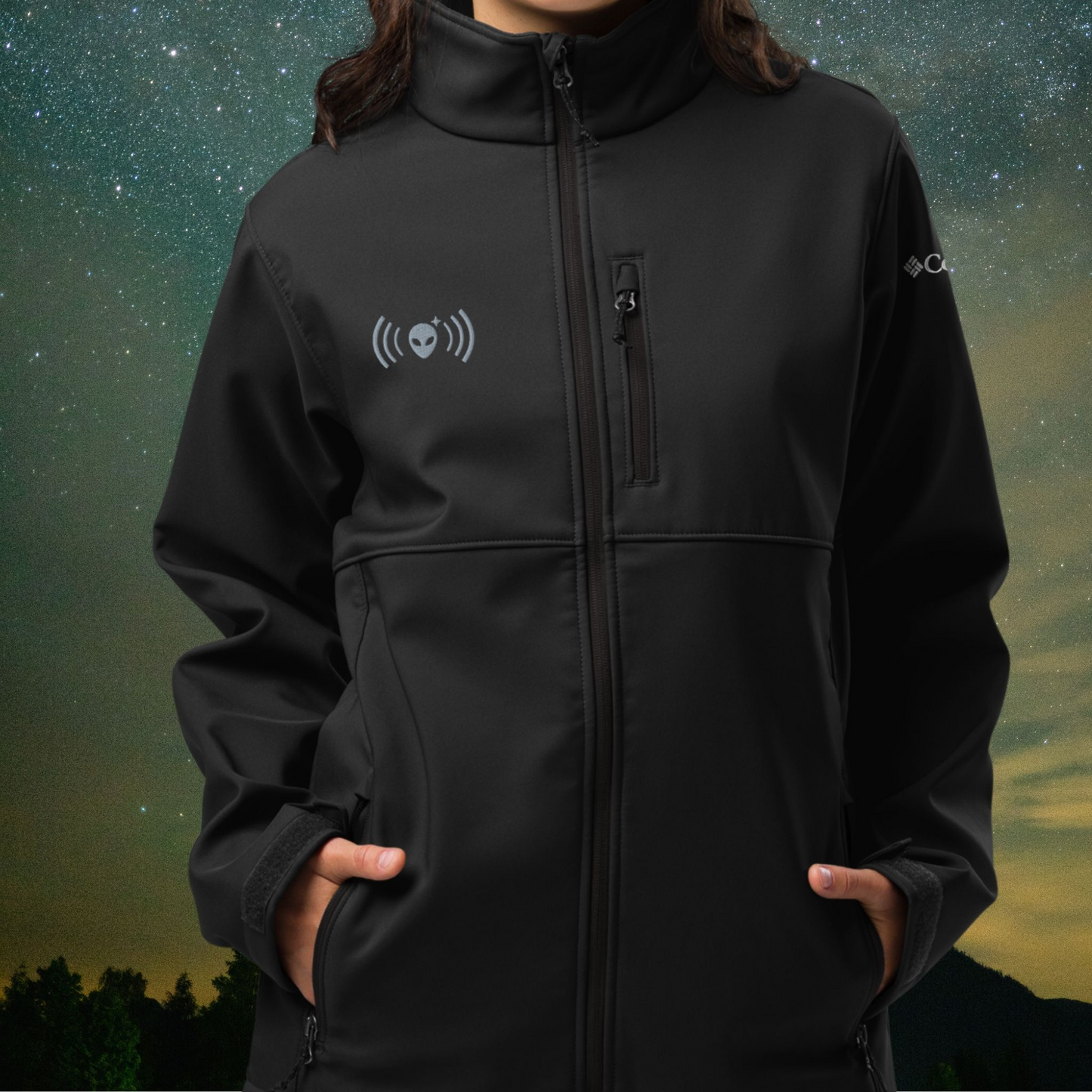 Person wearing a black Stellarwear jacket with an alien logo against a night sky background