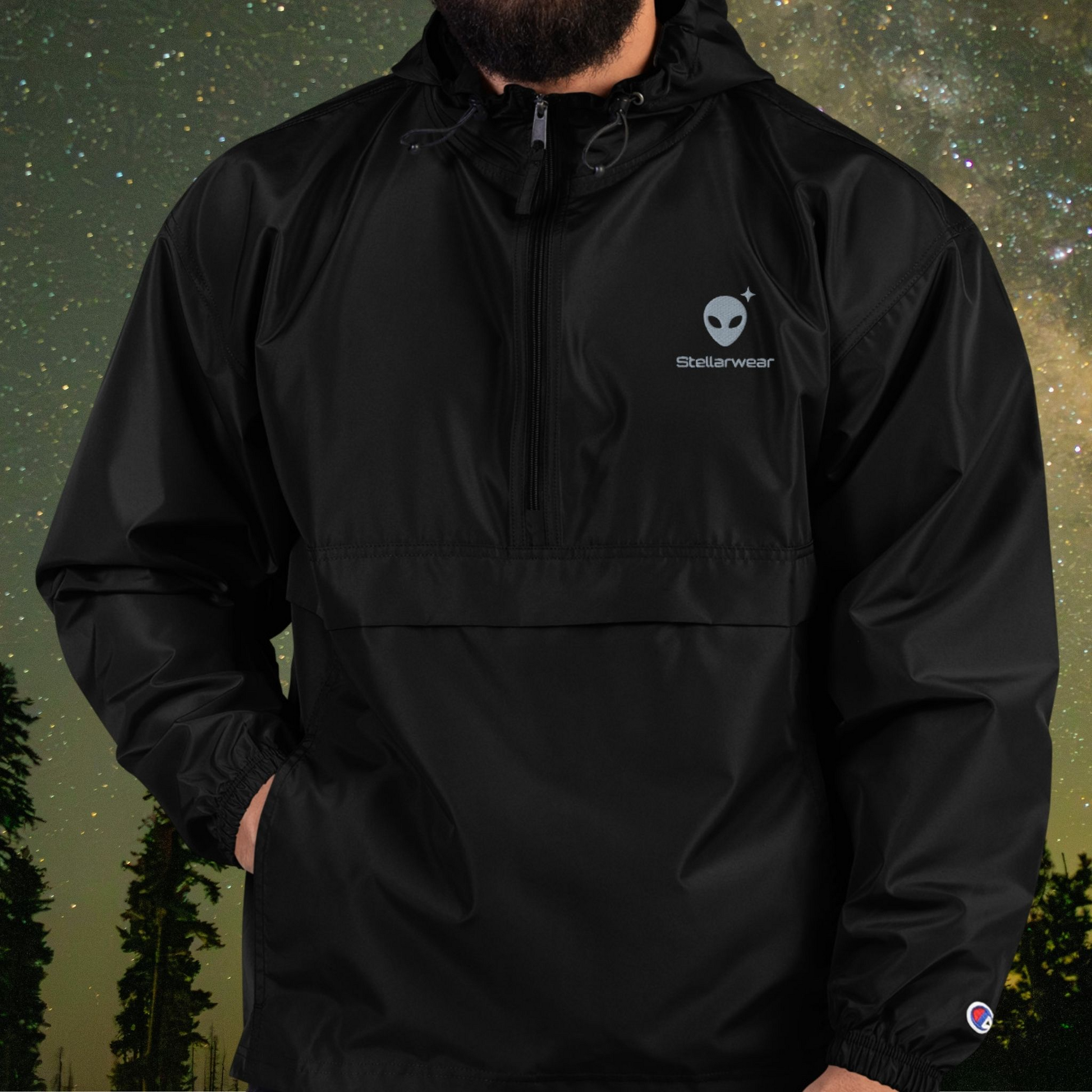 Person wearing a black Stellarwear jacket with alien logo against a starry night sky background