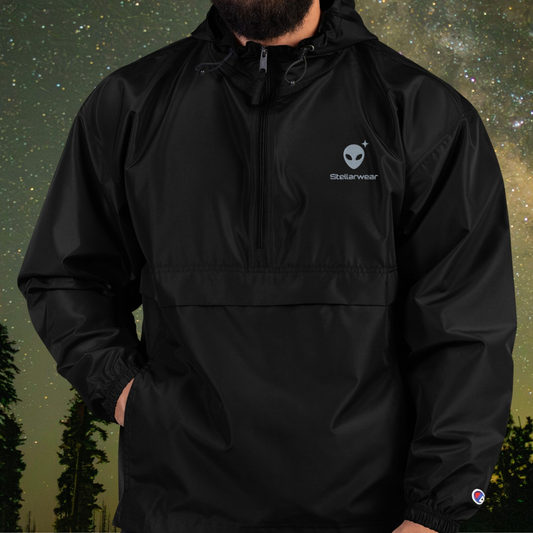 Person wearing a black Stellarwear jacket with alien logo against a starry night sky background