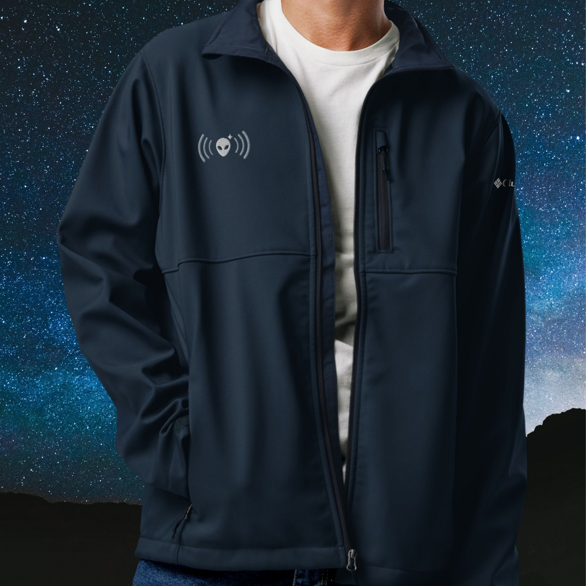 Person wearing a navy Stellarwear jacket with an alien logo against a starry night sky background
