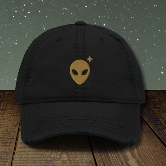 Black Stellarwear cap with alien emblem on a wooden surface and starry background