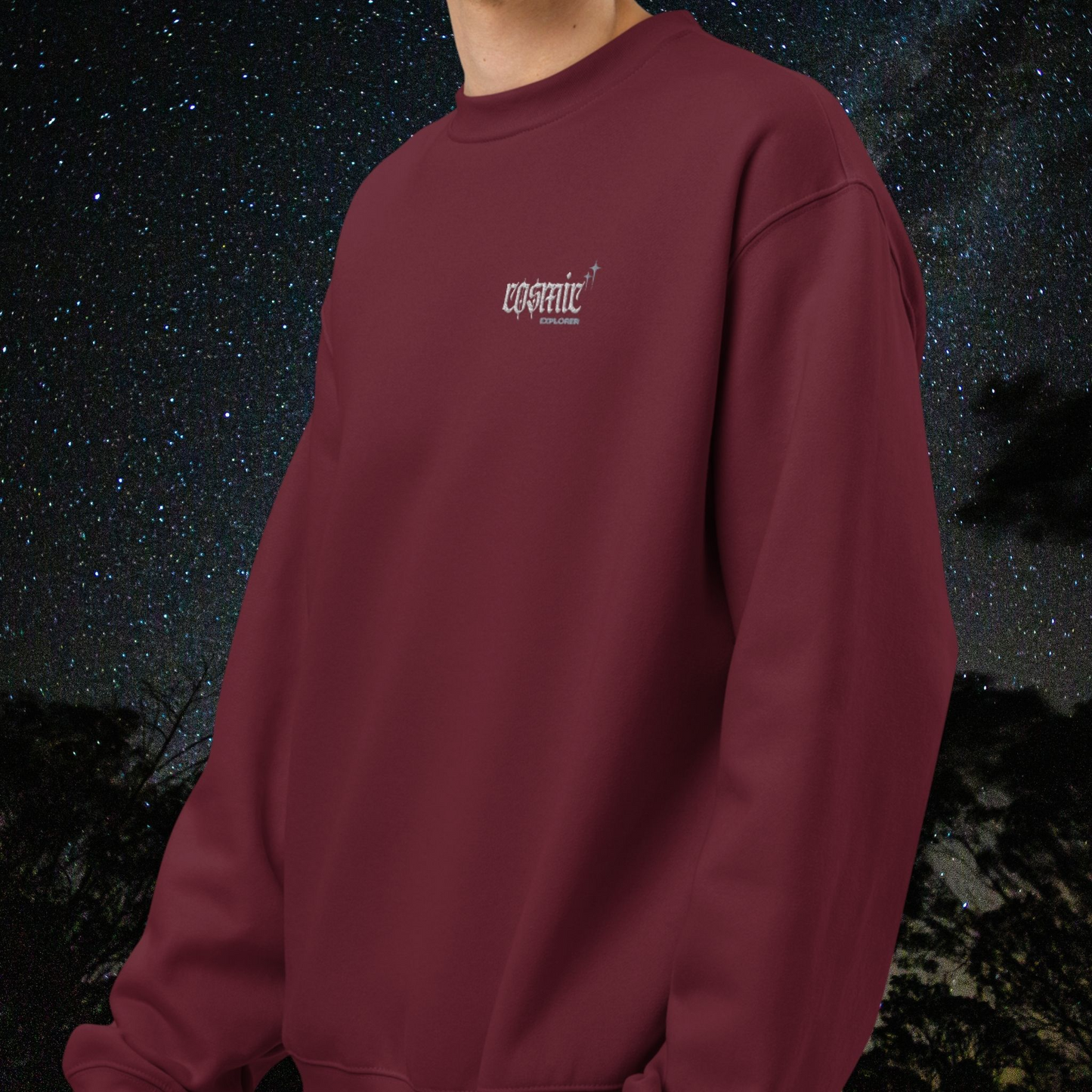 Person wearing a maroon Stellarwear sweatshirt with a cosmic logo against a starry night sky background