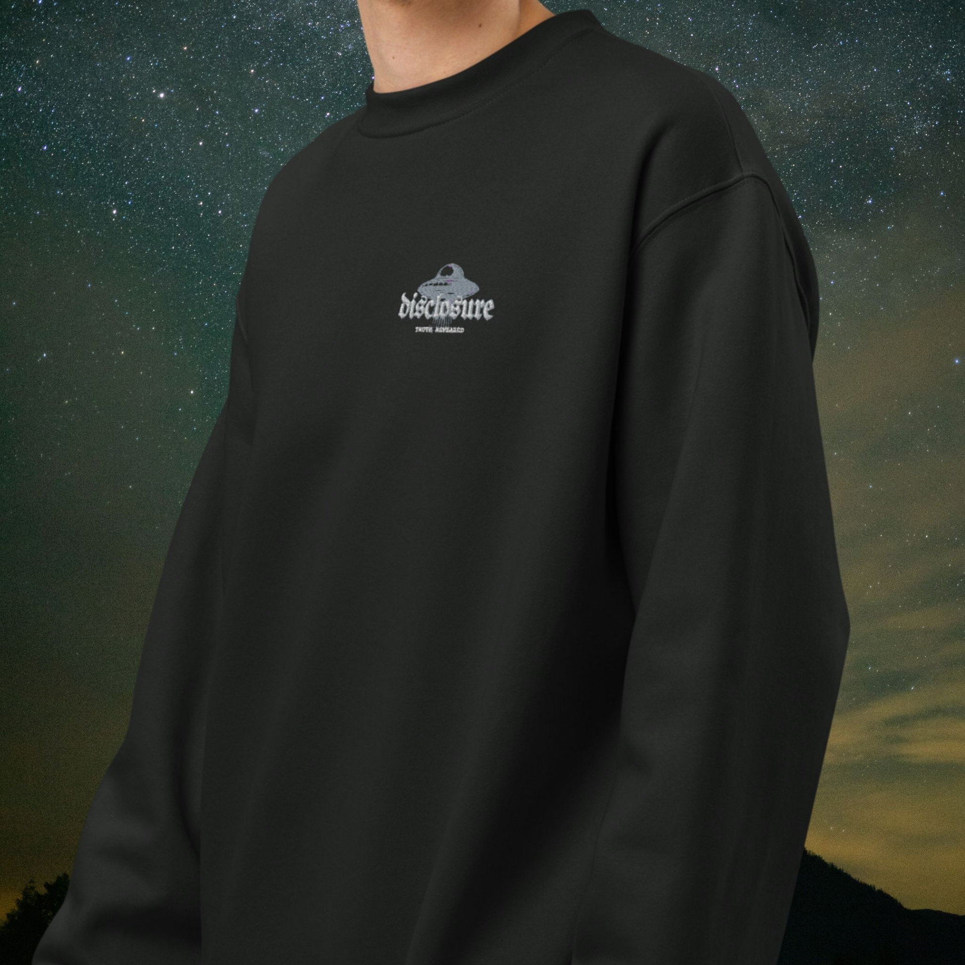 Black Stellarwear sweatshirt with a "disclosure" and UFO logo on the chest against a starry night sky background