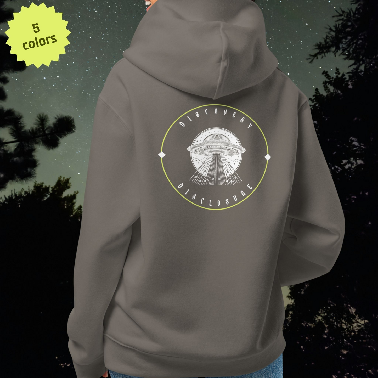 Gray Stellarwear hoodie with UFO design on the back, standing against a dark forest background.
