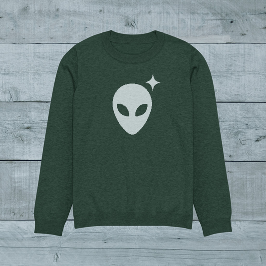 Green sweater with alien graphic on a wooden surface