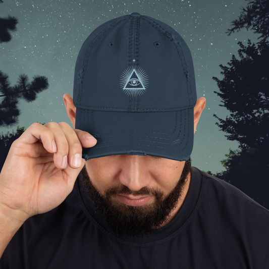 Man wearing a navy blue Stellarwear cap with a third eye logo against a night sky with trees
