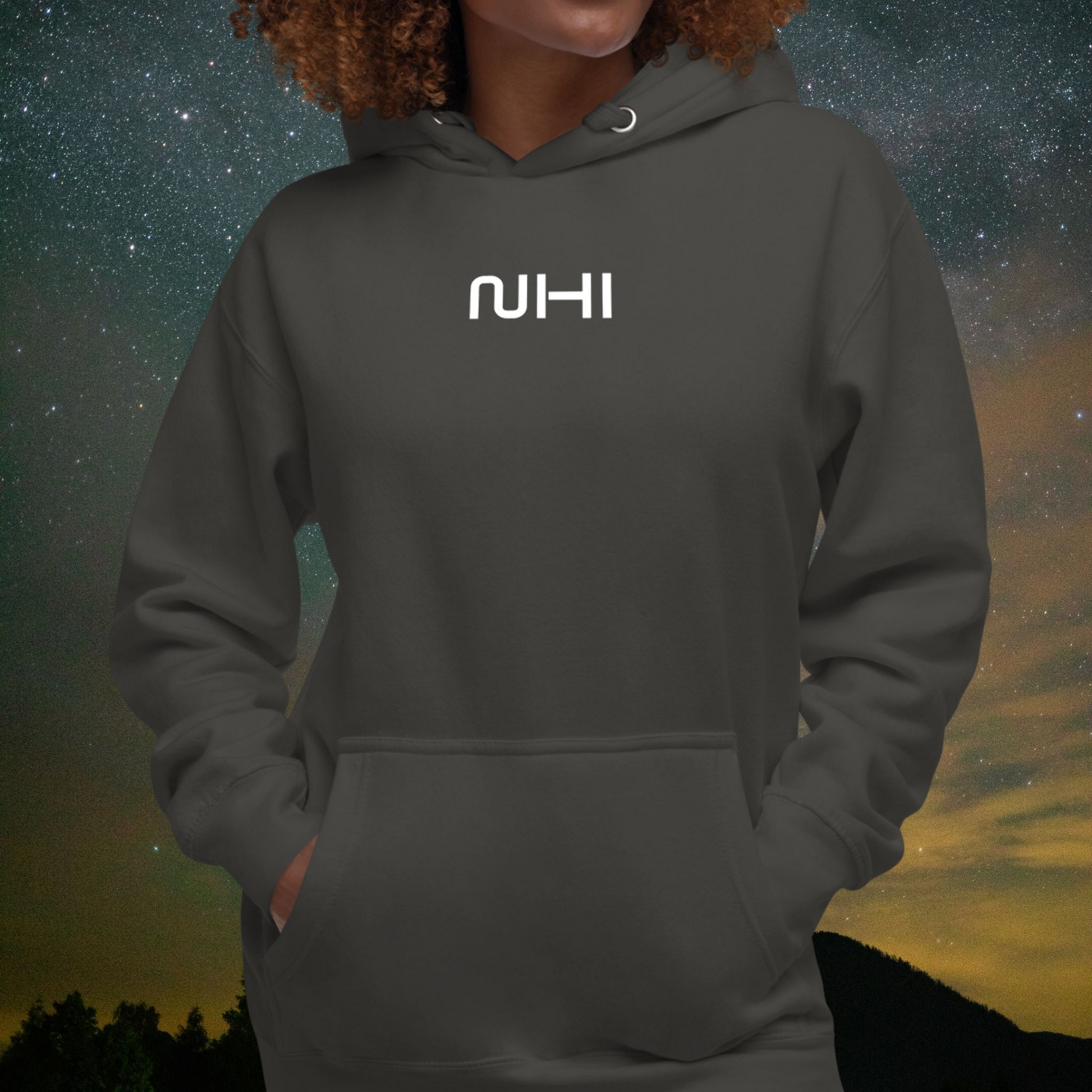 Person wearing a dark gray Stellarwear hoodie with 'NIHI' logo against a starry night sky