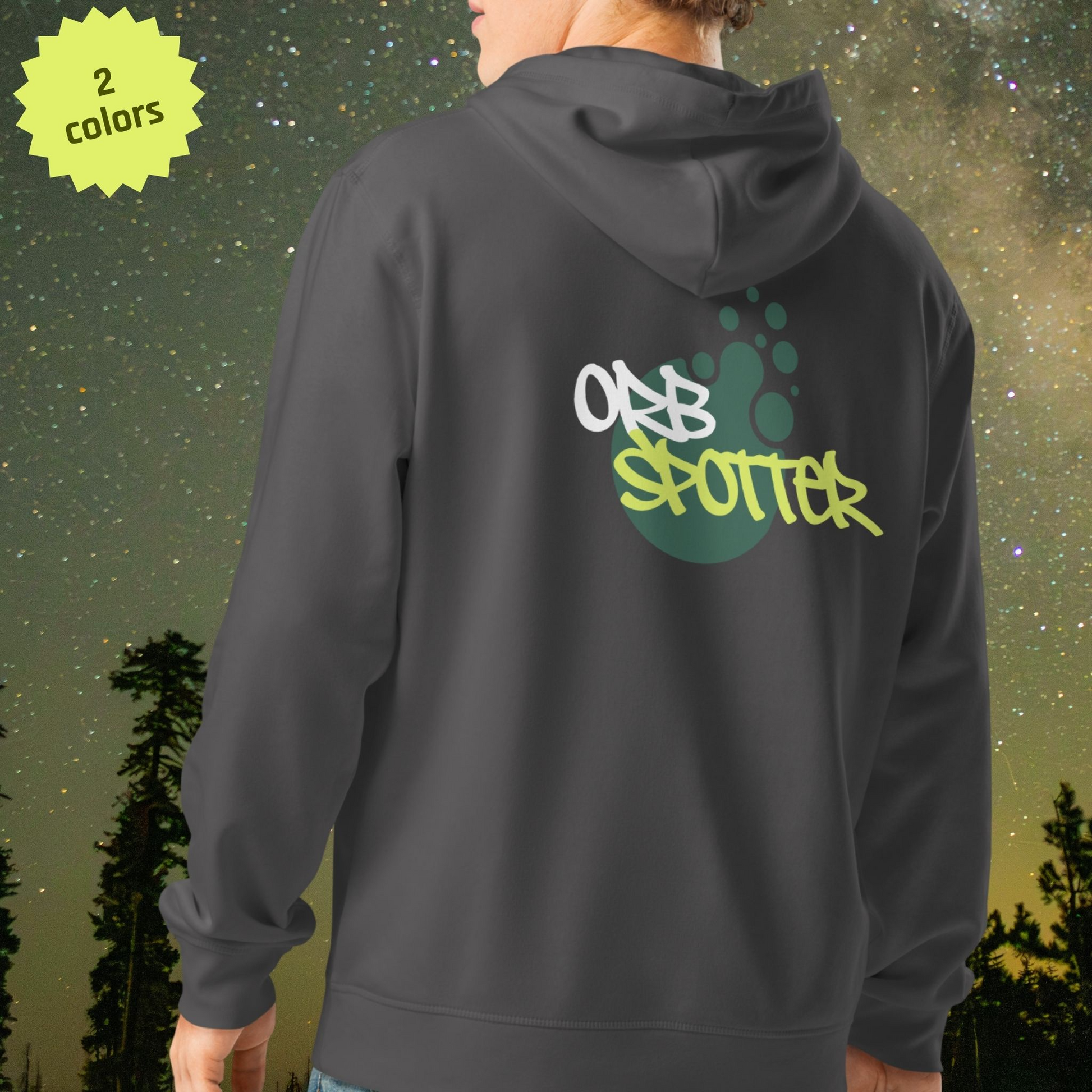 Person wearing a dark gray Stellarwear hoodie with 'Orb Spotter' text on the back, standing against a starry night sky.