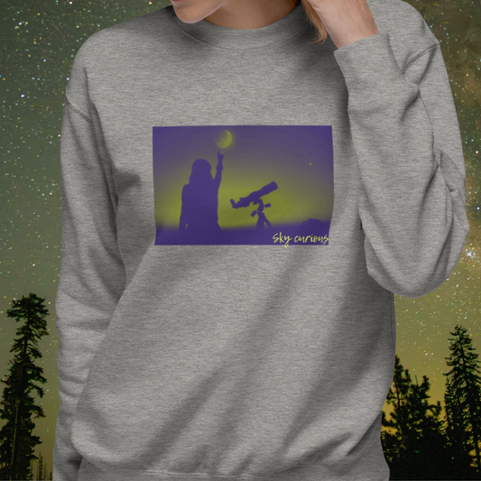 Gray Stellarwear sweatshirt with a graphic of a person with a telescope and the text 'Sky Curious' against a starry night sky background.