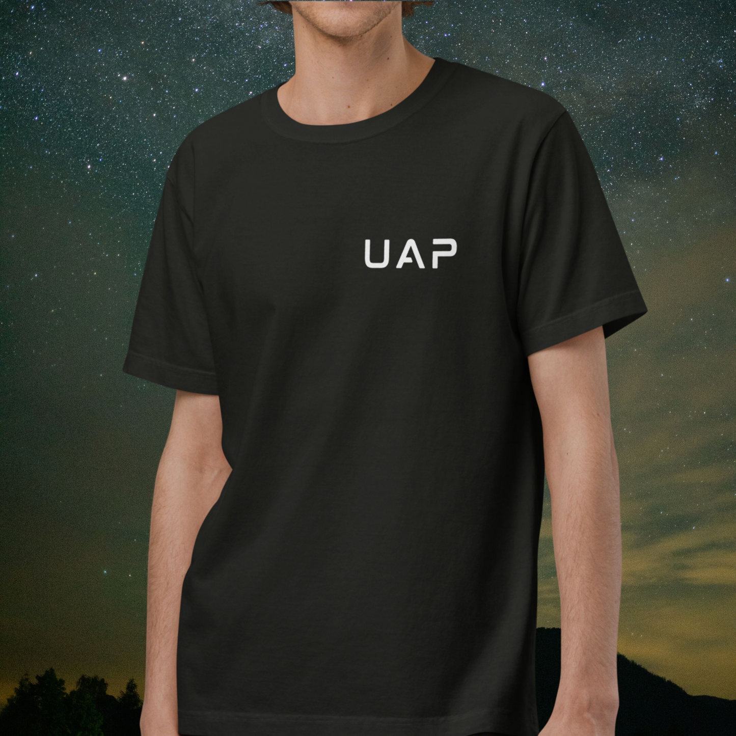 Person wearing a black Stellarwear t-shirt with 'UAP' logo against a starry night sky background