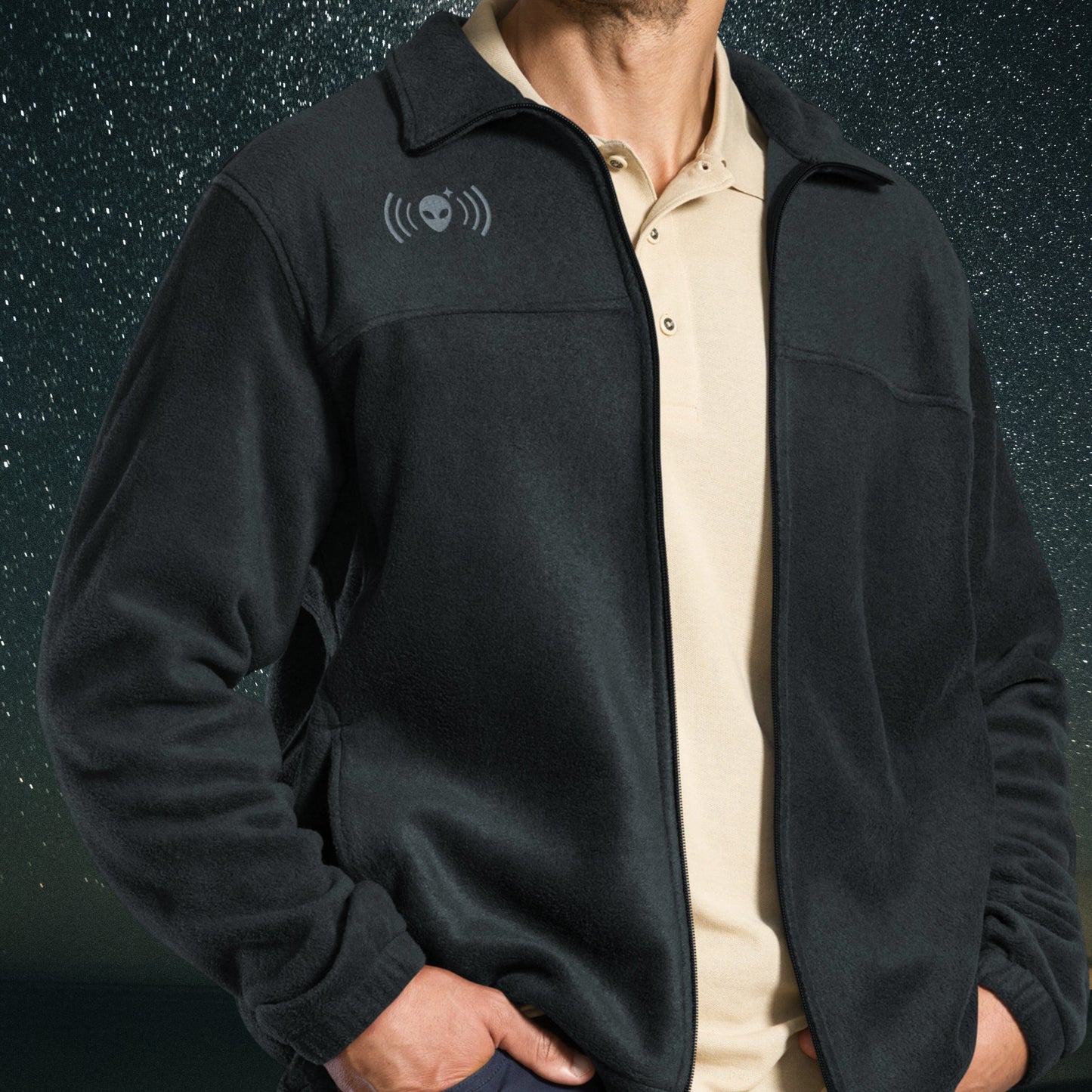 Person wearing a black Stellarwear jacket with an alien signal icon on the chest against a dark background