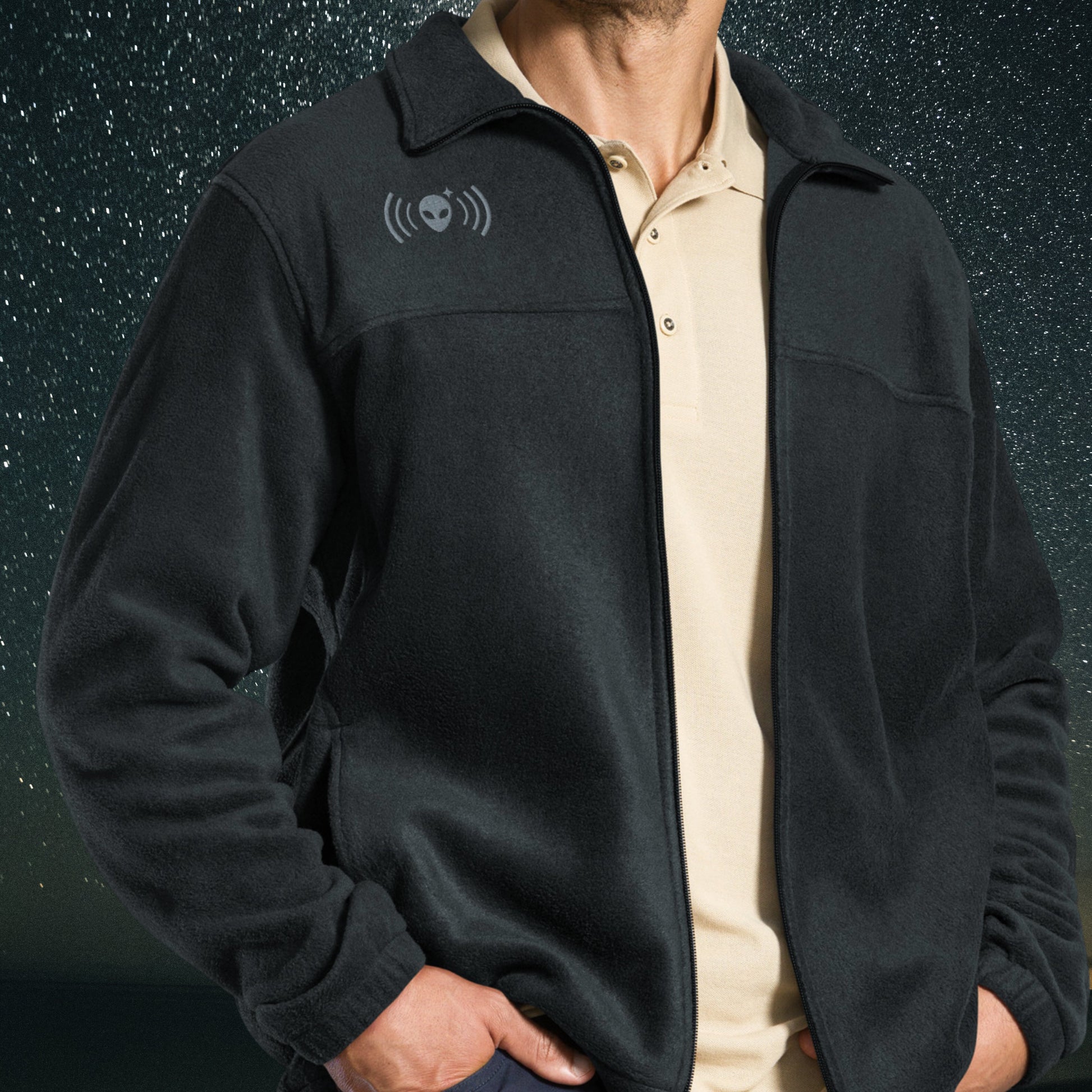 Person wearing a black Stellarwear jacket with an alien signal icon on the chest against a dark background