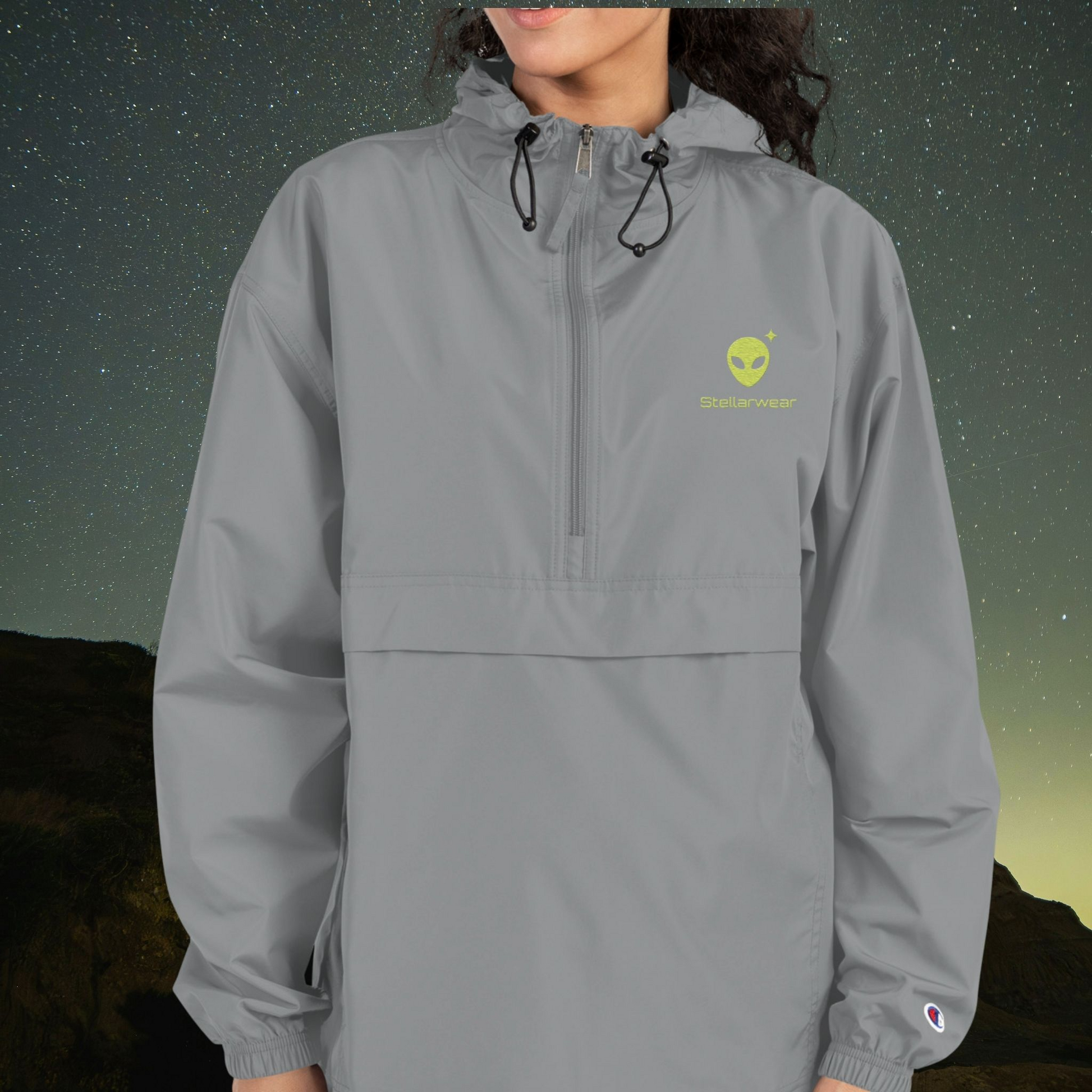 Person wearing a Stellarwear gray windbreaker with an alien logo on a starry night background